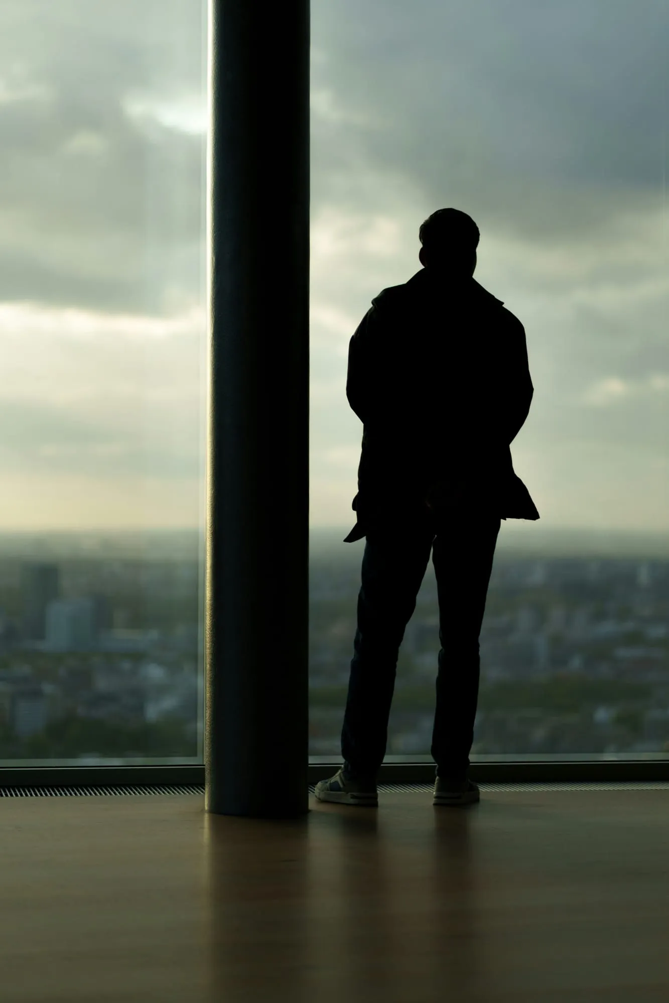 Silhouette eines Mannes am Fenster mit Blick über die Stadt